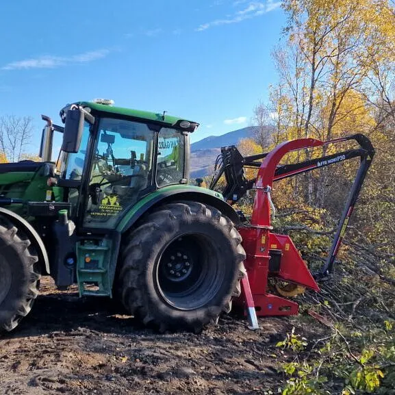 Traktor med flishugger i arbeid under rydding av skog og kratt i kupert terreng
