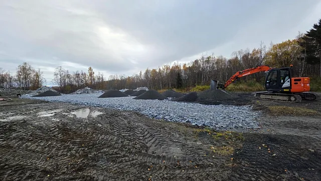 Oransje gravemaskin utfører grunnarbeid