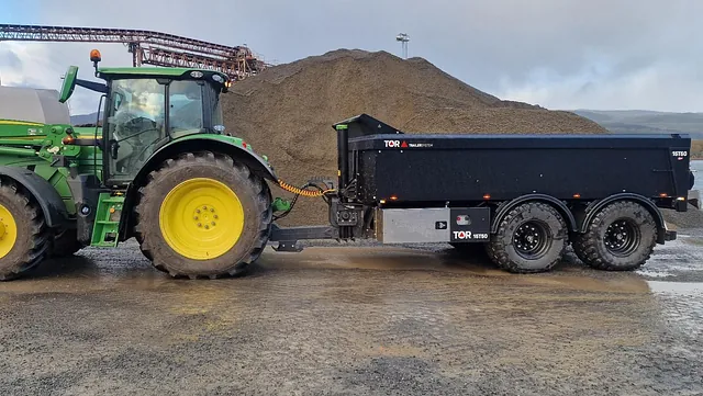 Grønn traktor med sort henger